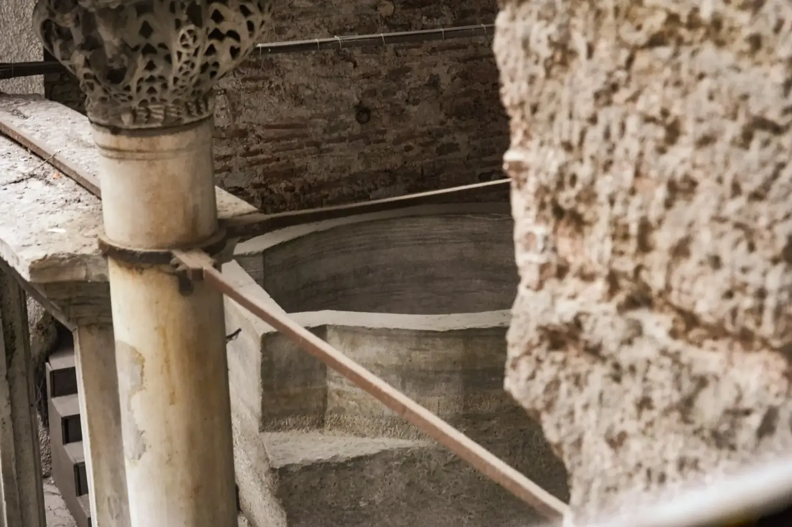 Una escalera de piedra junto a un capitel tallado, con el rebaje profundo a la vista.